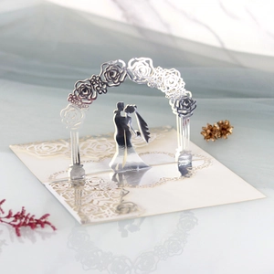 Detail showing laser-cut 3D pop-up wedding card with a romantic couple in a floral arch