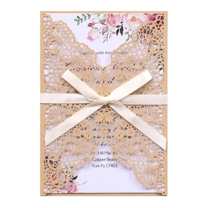 Détail de l'invitation de mariage découpée au laser avec motif fleuri et ruban crème