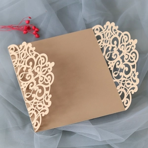 Detail of laser-cut champagne gold wedding invitation with elegant European scroll patterns