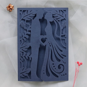 Detail of dark blue laser cut wedding card with silhouettes of couple and hearts