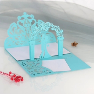Macro shot showing 3D laser-cut light blue wedding invitation with gate and couple silhouette