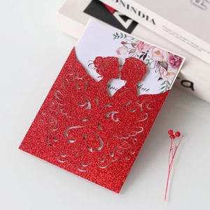 Detail of laser-cut red glitter wedding invitation with bride and groom silhouette