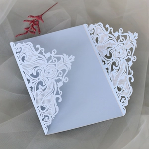 Close-up of laser-cut light blue wedding invitation with floral patterns and red dry flower