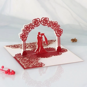 Detail of 3D wedding invitation featuring laser-cut red glitter floral arch and couple
