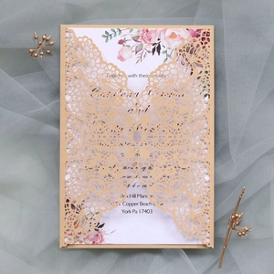 Détail macro du faire-part de mariage découpé au laser or champagne avec carte florale