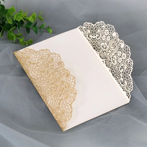 Macro shot of ivory laser-cut lace wedding invitation with sparkling gold glitter texture