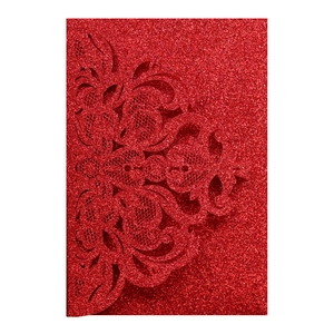 Close-up of laser-cut red glitter wedding invitation with intricate floral damask patterns