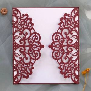 Macro detail of laser-cut burgundy invitation cover with elegant floral lace patterns
