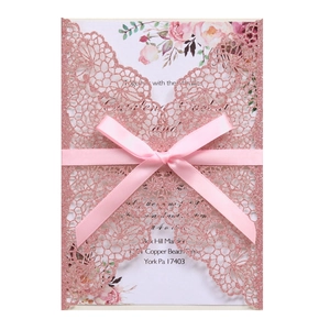 Detail of laser cut glitter wedding invitation with pink ribbon bow and floral inner card