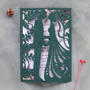 Intricate laser-cut wedding invitation featuring tree patterns and couple silhouettes