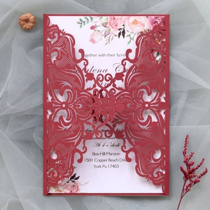 Macro detail of laser-cut burgundy wedding invitation featuring floral lace patterns