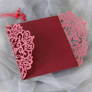 Detailed laser-cut floral pattern in rose gold on a burgundy wedding invitation card