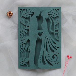 Detail of laser-cut dark green wedding invitation with elegant couple silhouette and heart