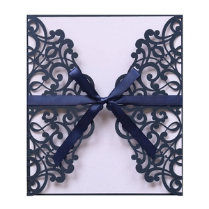 Detail of laser-cut navy blue wedding invitation cover with elegant ribbon bow