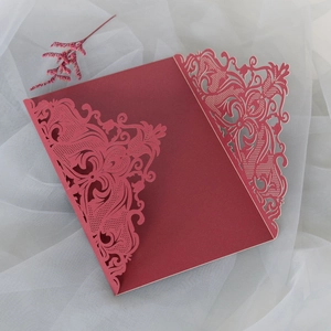Detail of laser-cut burgundy wedding invitation cover with intricate hollowed patterns