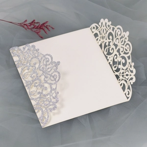 Detail of laser-cut wedding invitation with silver glitter floral pattern on cream paper
