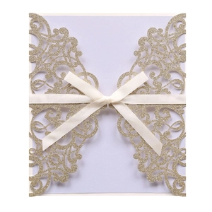 Detail of laser-cut glitter gold wedding invitation with lavender card and cream satin bow