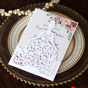 Detail of laser-cut white wedding invitation with hollow bride silhouette and floral patterns