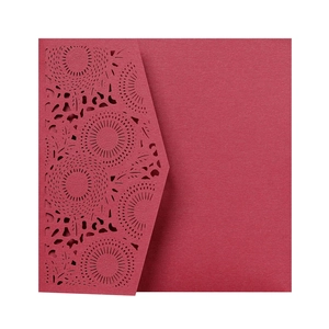 Detail of laser-cut geometric sunflower pattern on a deep red cardstock wedding invitation