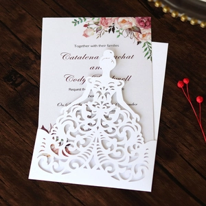 Detail of laser-cut wedding invitation with white dress hollow design on wood background