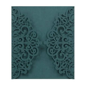 Detail of dark green laser cut wedding invitation with intricate scrollwork patterns