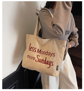 Detail of beige canvas tote bag featuring red embroidered text and high-quality fabric texture