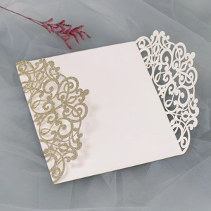 Detail of laser-cut wedding invitation cover with gold glitter and floral patterns
