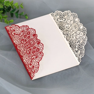 Close-up of laser-cut lace wedding invitation with gold glitter and elegant ivory patterns