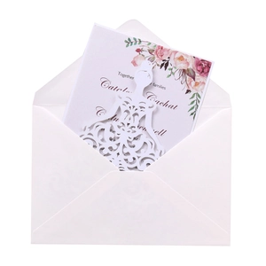 Detailed view of white laser-cut bridal gown invitation and pink rose floral card
