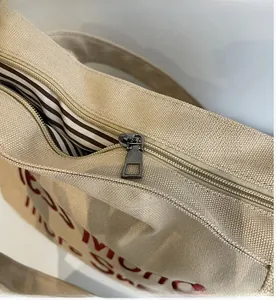 Close-up of smooth silver metal zipper and striped lining on beige canvas tote bag