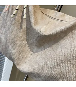 Detail einer beigen Jacquard-Tasche mit Blattstruktur und geflochtener Kordelverzierung