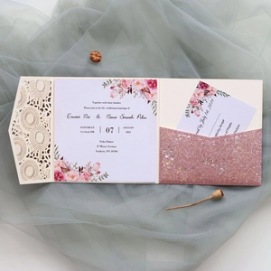 Détail de l'invitation en dentelle ivoire découpée au laser avec paillettes or rose et fleurs