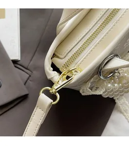 Detail of cream white bag with gold zipper, elegant lace trim and pearl pendant charms