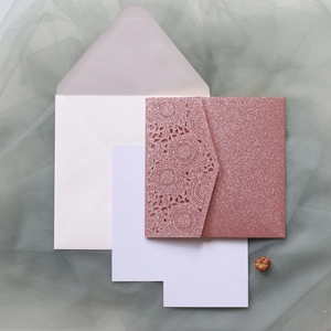 Détail de l'invitation de mariage ajourée en paillettes or rose avec cartes internes