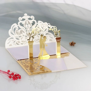 Macro shot showing 3D laser-cut lace wedding card with gold couple silhouette