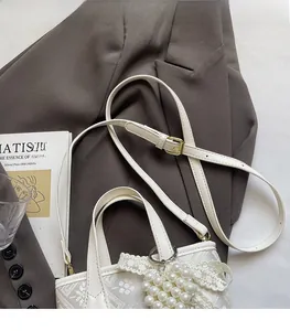 Detail of white jacquard bucket bag featuring lace trim and a pearl heart charm