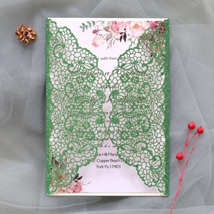 Detail of laser-cut glitter wedding invitation with green lace cover and floral insert