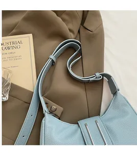 Détail du sac croissant bleu clair en cuir grainé avec boucles métalliques argentées