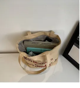 Interior view of large capacity beige tote bag showing books and a laptop inside
