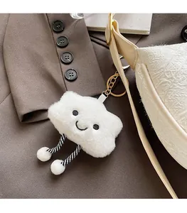 Close-up of fluffy white cloud charm with golden keychain on a textured handbag