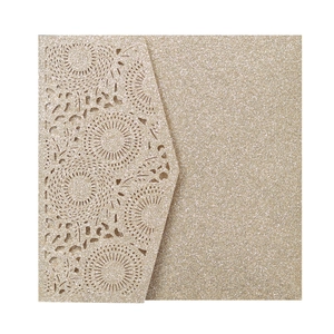 Détail macro de l'invitation de mariage en papier pailleté or champagne découpé