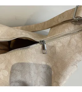 Detail von silbernem Reißverschluss und beigem Jacquard-Gewebe der Achseltasche