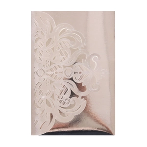 Detail of rose gold laser-cut invitation cover with intricate floral and scroll patterns