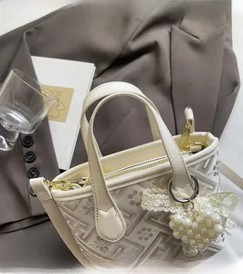 Detail of vintage beige tote bag with floral patterns and pearl bow charm accessory