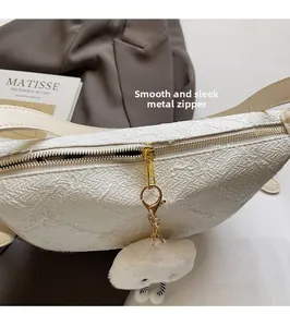 Detail of white dumpling bag with floral embossing and plush cloud charm accessory