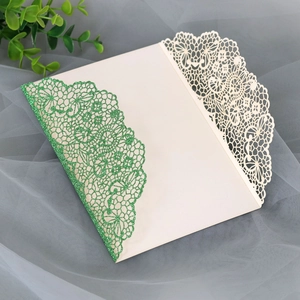 Detail of glitter green laser cut lace patterns on a wedding invitation envelope