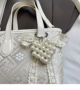 Close-up of jacquard fabric handbag featuring a pearl heart charm and lace details