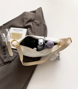 Internal capacity of the white hobo bag showing a phone, umbrella, and skincare items