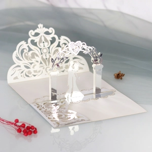 Detail of 3D laser-cut wedding card featuring a couple under a white floral archway