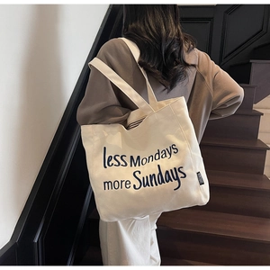 Detail of canvas tote bag with less Mondays more Sundays embroidery and shoulder strap